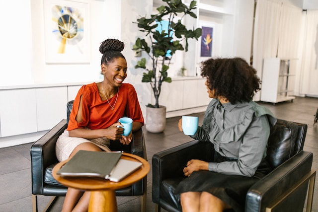 two people talking and smiling while drinking coffee